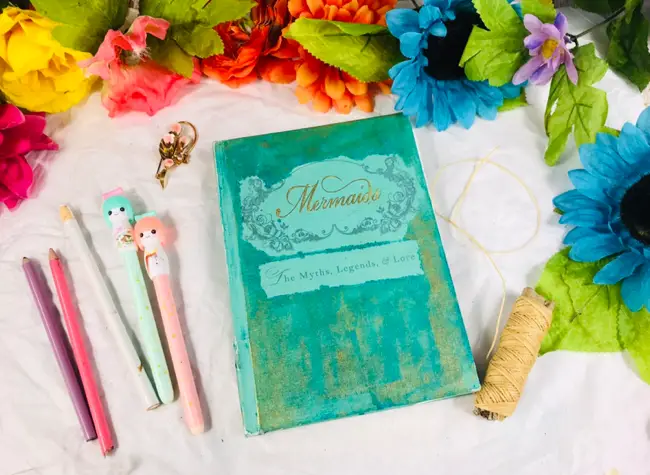 DIY Sketchbook next to pencils, pens, and flowers