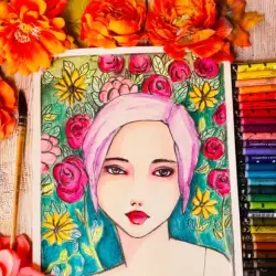 art journal page of girl surrounded by flowers. Art journal page is next to a paint brush, flowers and Neocolor II pallet